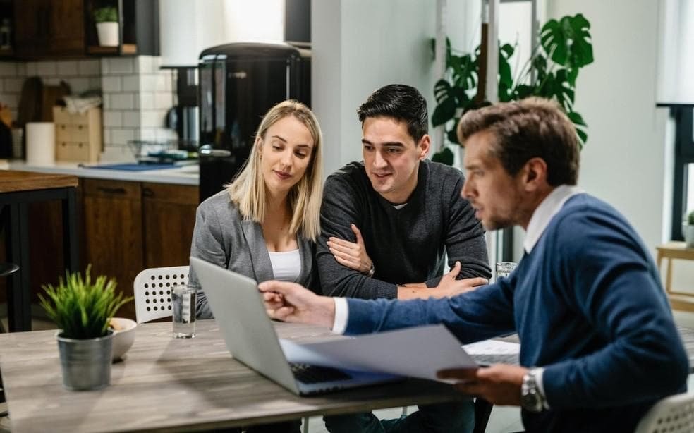 Real estate agent discussing property purchase documents with buyers inside a modern house in Brazil.